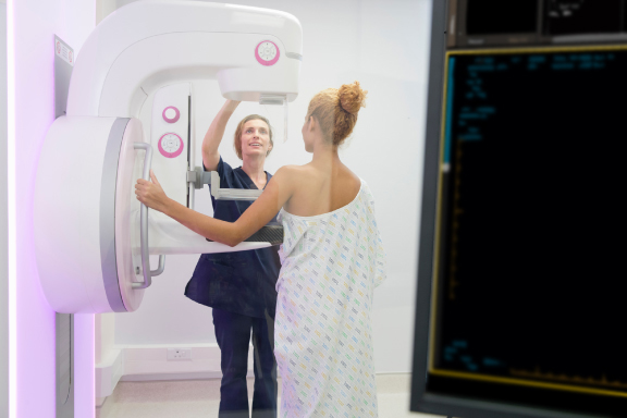 Radiographer is operating the mammogram system while the patient is waiting